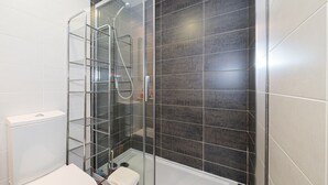 A modern bathroom with a glass-enclosed shower, a white toilet, and a metal shelf unit. - Apartamento Mariphils (Linnea Sol) (Orihuela Costa)