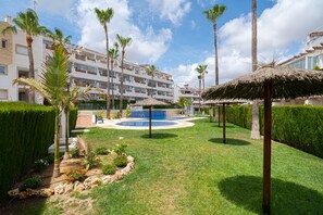 A resort with a swimming pool, palm trees, and a building with multiple balconies.