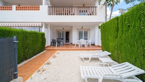 A two-story building with a covered patio area featuring outdoor furniture and a gravel pathway. - Apartamento Mariphils (Linnea Sol) (Orihuela Costa)