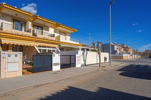 Un immeuble d’habitation doté d’une entrée sécurisée, d’un balcon et surplombant un ciel d’un bleu éclatant.