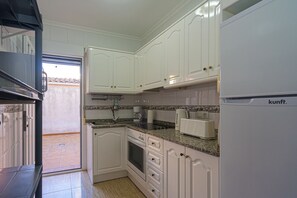 A kitchen with white cabinets, a built-in oven, a microwave, and a refrigerator.