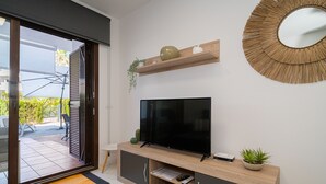 Un salon moderne doté d’un téléviseur à écran plat, d’un meuble de rangement en bois et d’un grand miroir.