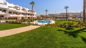 Un hôtel doté d’une piscine, de palmiers et d’une pelouse bien entretenue.