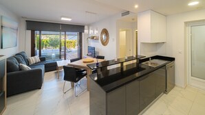 Une cuisine moderne dotée d’un îlot central, d’un coin repas avec un canapé et des chaises, et offrant une vue à travers les portes vitrées.