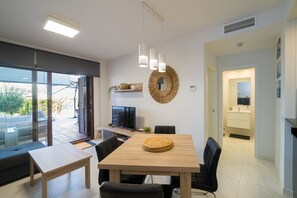 A modern dining area with a wooden table, black chairs, a television, and a large mirror on the wall.