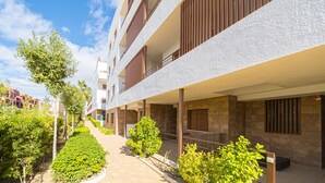A modern building with multiple balconies, a paved pathway, and well-maintained greenery. - Apartamento Fleur et Soleil (Orihuela Costa)