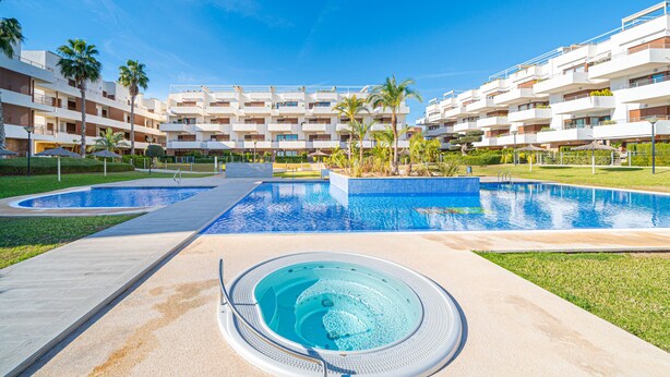 A hotel with multiple balconies, a central swimming pool, and a hot tub area. - Apartamento Fleur et Soleil (Orihuela Costa)