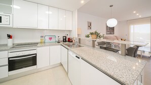 A modern kitchen with white cabinetry, a built-in oven, and a dishwasher. - Apartamento Fleur et Soleil (Orihuela Costa)