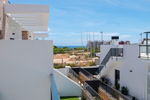 Un bâtiment moderne à la façade blanche, doté d’une terrasse sur le toit et offrant une vue sur la mer.