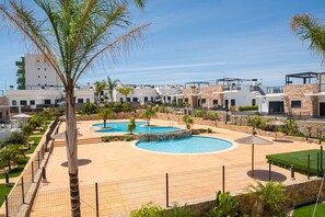 Een resort met diverse zwembaden, palmbomen en moderne gebouwen.