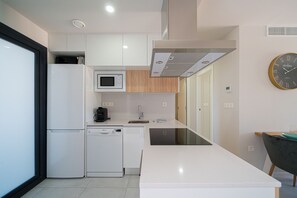 Een moderne keuken met witte kasten, een magnetron, een koffieapparaat en een vaatwasser.