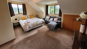 Een slaapkamer met een bed, een bank, een bureau en een kast.