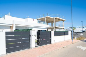 A modern building with a gated entrance, numbered 48 and 46, and a covered walkway above.