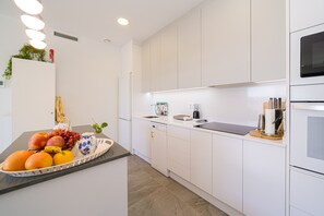 A modern kitchen with white cabinetry, a black countertop, and a built-in oven.