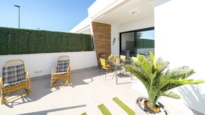 A modern outdoor patio with wicker chairs, a dining table, and a potted plant.