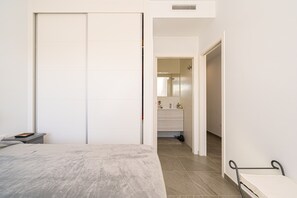 A bedroom with a bed, a bedside table, a wardrobe, and a bathroom visible through an open door.