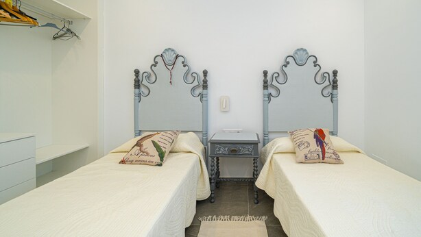 A twin bedroom with two beds, a small bedside table, and a wall-mounted telephone.