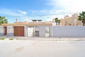 A two-story building with a tiled roof, a gated entrance, and a paved driveway.