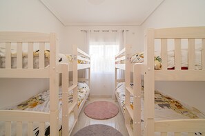 A room with bunk beds, a round rug, and a window with curtains.
