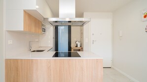 Une cuisine moderne dotée d’un îlot central, d’appareils électroménagers en acier inoxydable et de meubles de rangement en bois.