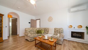 A living room with a wooden coffee table, two patterned sofas, a fireplace, and a decorative wall piece.