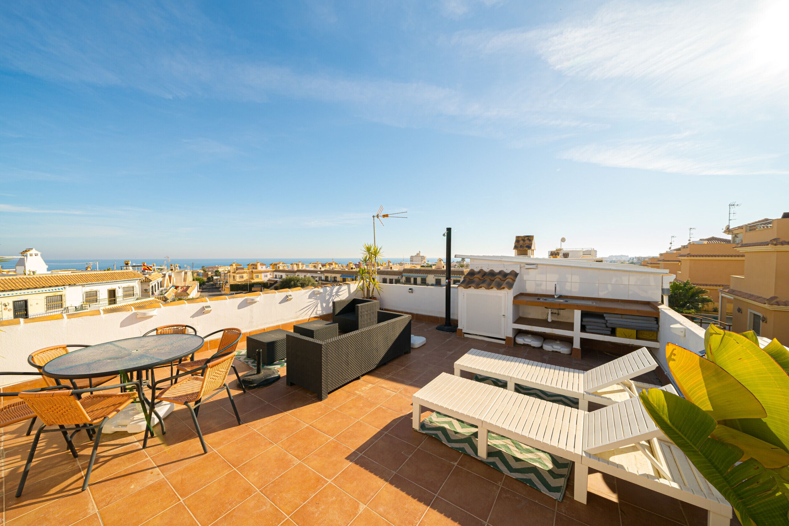 Une terrasse sur le toit avec une table et des chaises, un canapé et un petit espace aménagé en jardin.