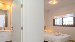 A modern hotel room with a white bed, a bedside lamp, and a window with a view of the outside. - Apartamento Luna (Mar de Pulpi) (San Juan de los terreros)