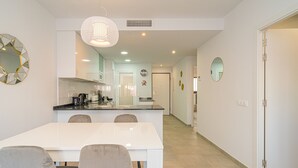 A modern kitchen with a dining area, white walls, and a clean, minimalist design. - Apartamento Luna (Mar de Pulpi) (San Juan de los terreros)