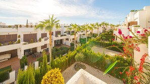A rooftop garden with palm trees, a seating area, and a view of the surrounding buildings. - Casa Musica (Mar de Pulpi) (San Juan de los terreros)