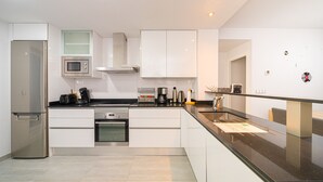 A modern kitchen with white cabinetry, stainless steel appliances, and a black countertop. - Casa Musica (Mar de Pulpi) (San Juan de los terreros)