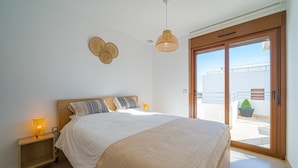 A bedroom with a large bed, a nightstand with a lamp, a ceiling fan, and a sliding glass door to an outdoor balcony. - Sole Mio (Terrazas de Campoamor) (Orihuela Costa)