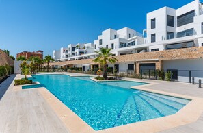 A modern hotel with a swimming pool, stone facade, and multiple balconies. - Apartamento Azahar (Villamartin) (Orihuela Costa)