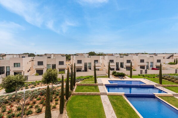 A modern residential complex with multiple apartment buildings, a swimming pool, and well-maintained gardens.