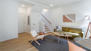 A modern living room with a staircase, a sofa, a coffee table, and a chair. - Basecamp - a PMI Scenic City Vacation Rental (Chattanooga)