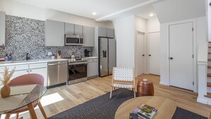 A modern kitchen with stainless steel appliances, a dining area with a glass table, and a cozy seating arrangement. - Basecamp - a PMI Scenic City Vacation Rental (Chattanooga)