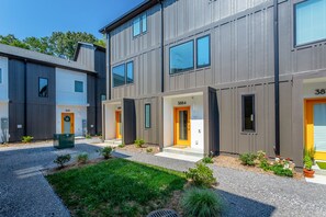 A modern multi-story building with numbered doors, a well-maintained lawn, and small plants. - Basecamp - a PMI Scenic City Vacation Rental (Chattanooga)