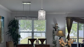 A dining area with a table, chairs, a chandelier, a lamp, and a view of the outdoors. - Boho Gator Lux 2 Ft. Myers (Lehigh Acres)