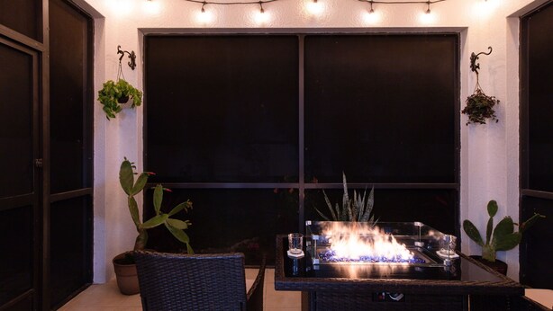 An outdoor seating area with a fire feature, wicker chairs, and potted plants. - Boho Gator Lux 2 Ft. Myers (Lehigh Acres)