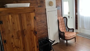 A room with wooden walls, a white door, a cushioned chair, and a white cabinet.