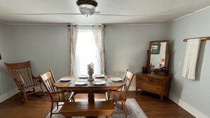 A dining room with a wooden table set for four, flanked by two wooden chairs, a bench, and a wooden sideboard with a mirror.