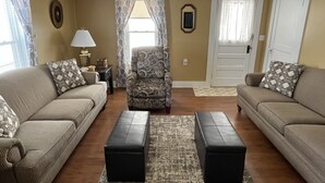 A living room with two sofas, a patterned armchair, a coffee table, and a rug.