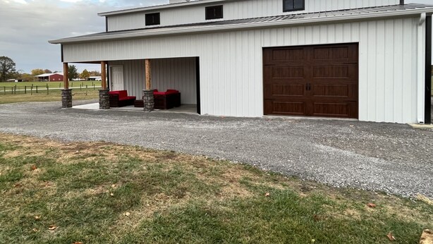 A white building with a covered porch, two chimneys, and a large garage door.