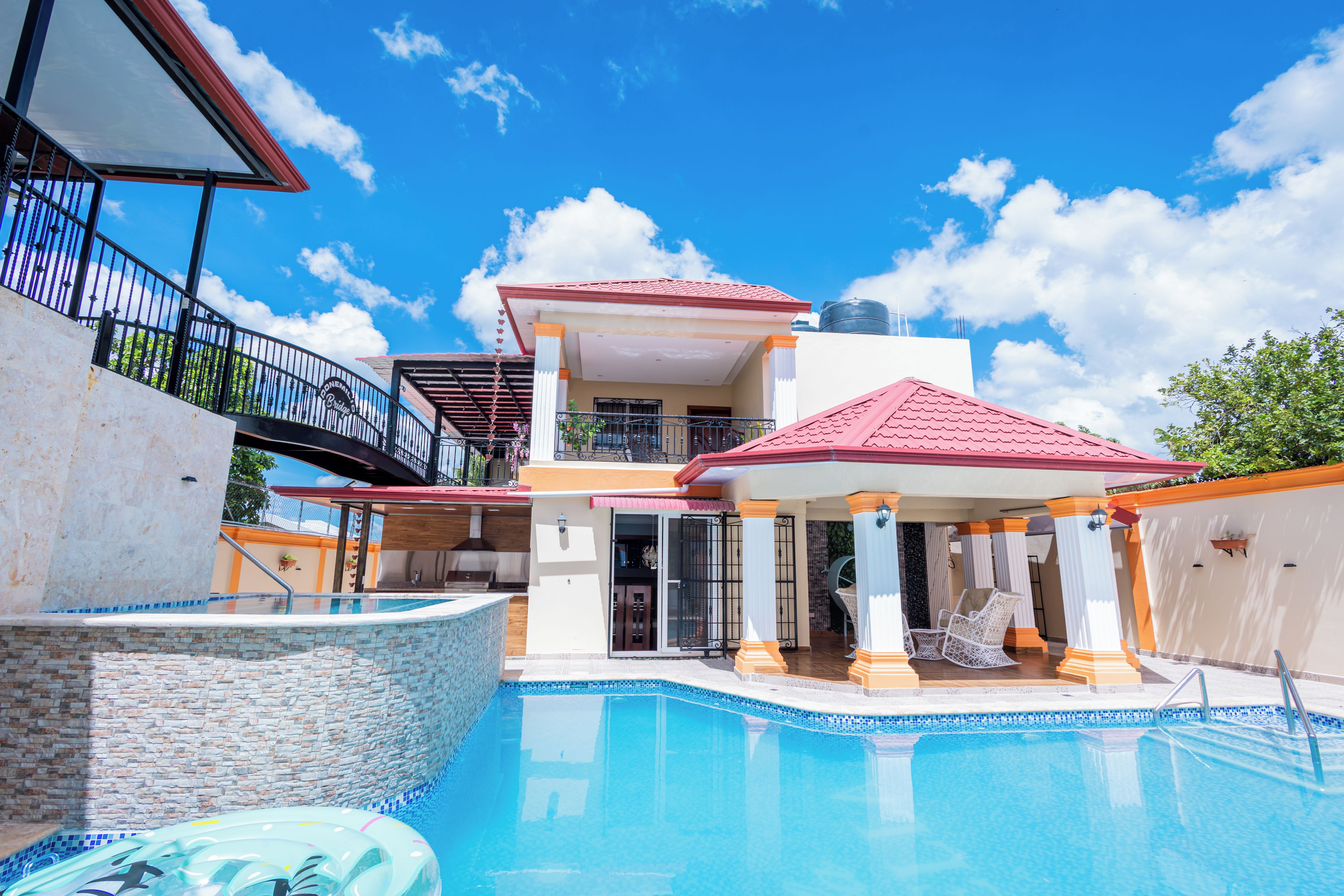 Une maison à deux étages avec une piscine, un patio couvert et un balcon.