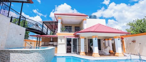 A two-story house with a swimming pool, a covered patio, and a balcony.