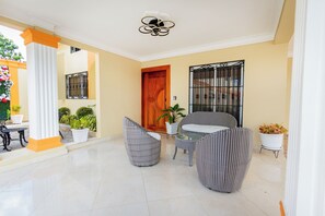A spacious indoor area with a tiled floor, a wooden door, and a balcony with potted plants.