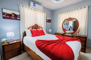 Habitación de hotel con cama, mesitas de noche, un espejo y aire acondicionado de pared.