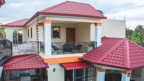 A two-story house with a balcony, a swimming pool, and a barbecue area.