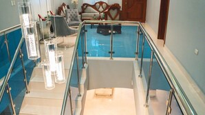 A modern hotel interior with a glass railing, a staircase, and a pool area.
