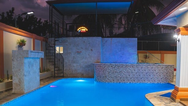 An outdoor swimming pool with a rubber duck, a staircase, and a bar sign in the background.
