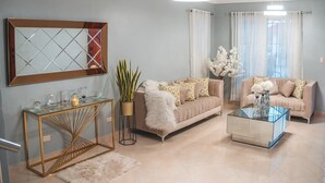 A living room with a sofa, a coffee table, a console table, a mirror, and a potted plant.